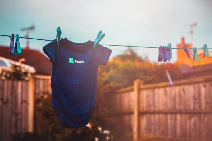 A screen-printed onesie hanging on an outdoor clothesline.