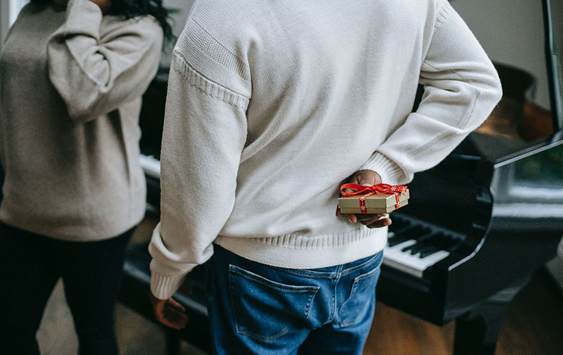 A man holding a Christmas gift behind his back