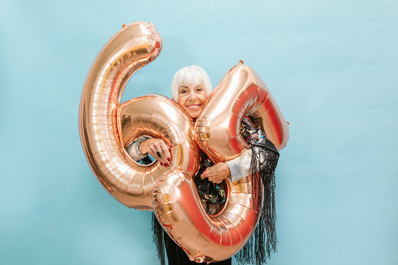 A woman holding two numbered balloons on her 65th birthday