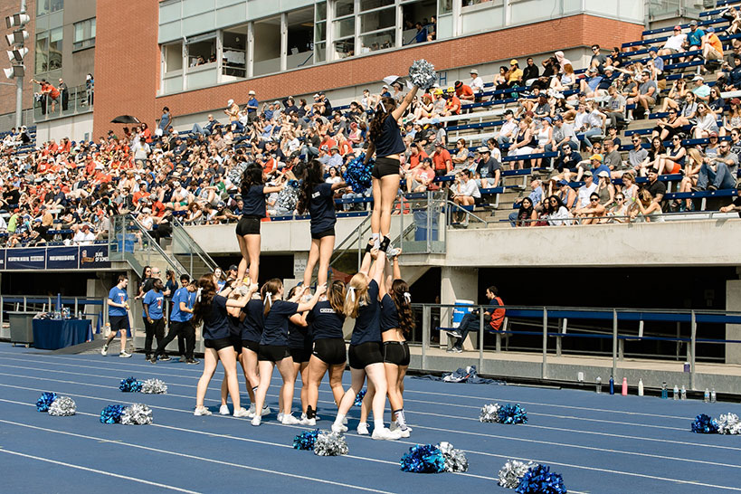Cheerleaders in front of a crowd at a school track meet