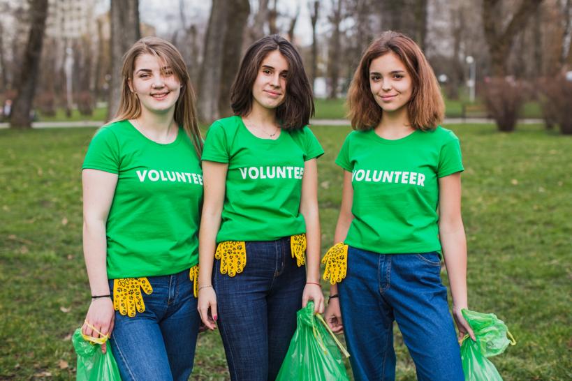 Three volunteers wearing green shirts with white lettering