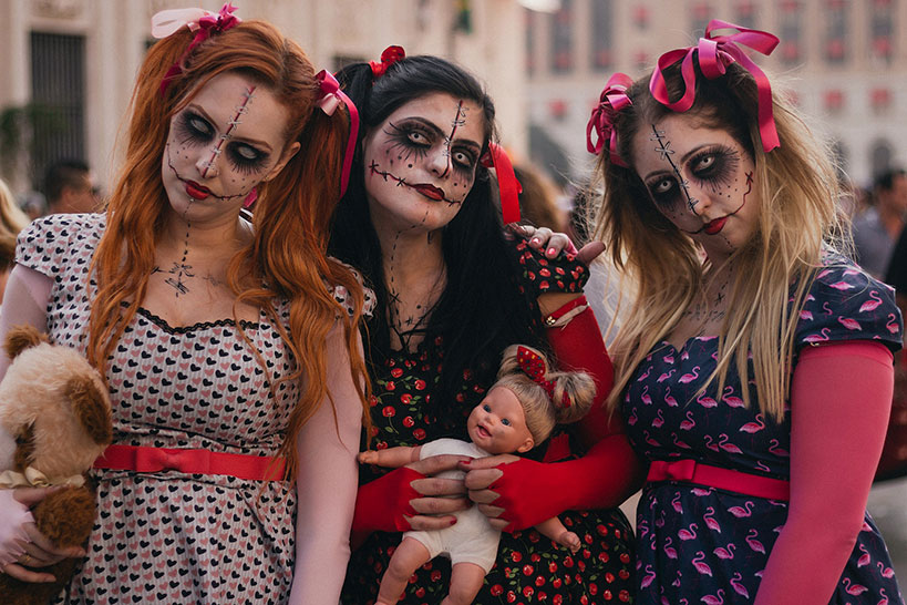 Three women wearing makeup in a unified Halloween costume theme