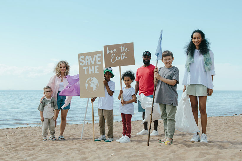 Young environmentalists hold signs on a beach